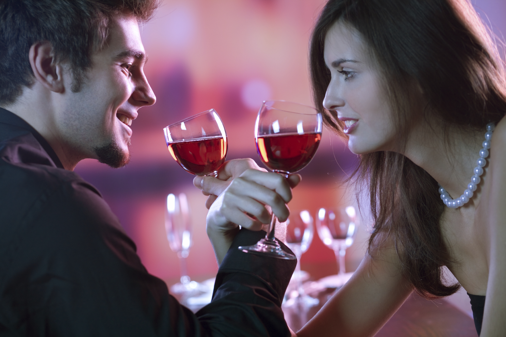 Young couple sharing a glass of red wine in restaurant, celebrating or on romantic date